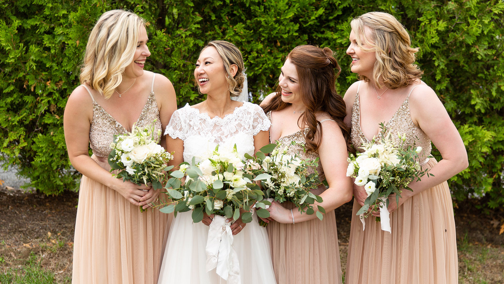 Bride and bridesmaids laughing while holding bouquets 