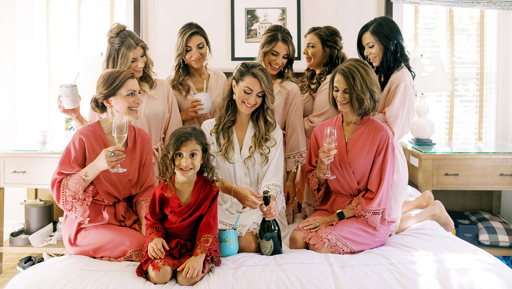 Bridal party on top of bed opening champagne