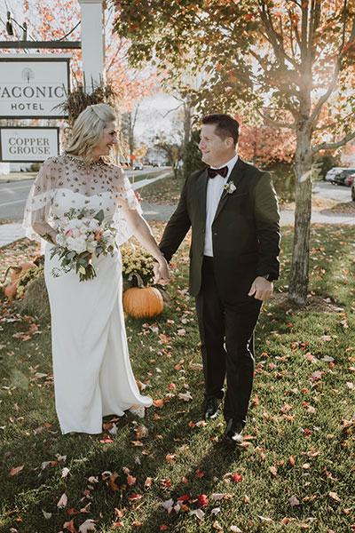 Bride and groom holding hands in front of Taconic sign