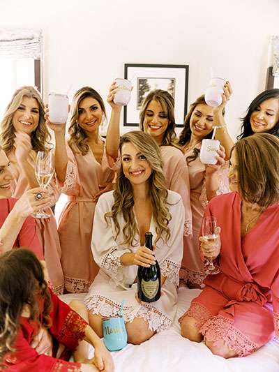 Bridal party on top of bed toasting with champagne