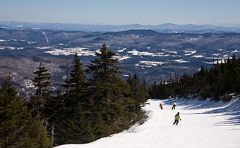 people skiing down slopes with a mountain view