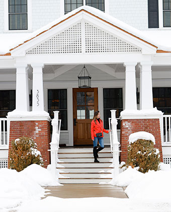 a person walking up stairs in front of a house in white snow